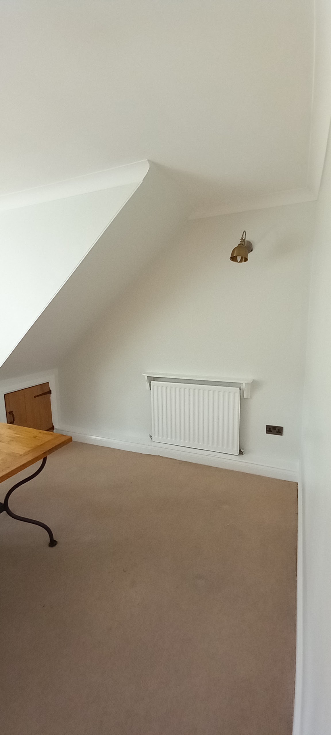 A loft bedroom freshly painted with a radiator under the window
