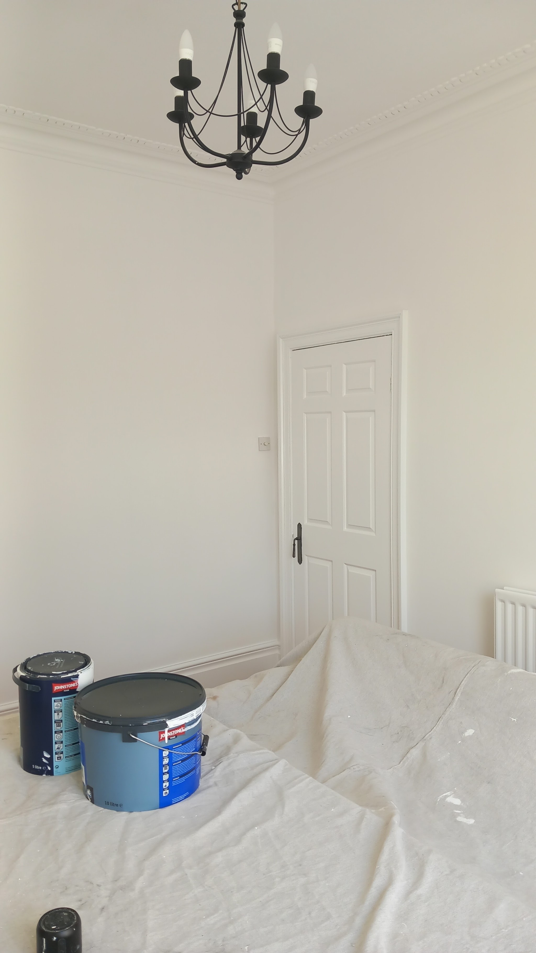 A white-painted room with a chandelier and a panelled door